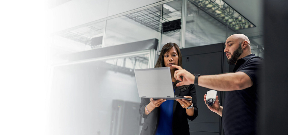 Two security professionals review a laptop and a camera, showing flexible security solutions that avoid vendor lock-in.
