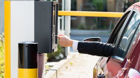 Un conductor pagando mientras está en su auto para ingresar a un estacionamiento