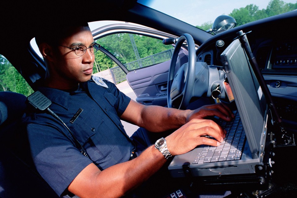 Agente di polizia che inserisce dati in auto.