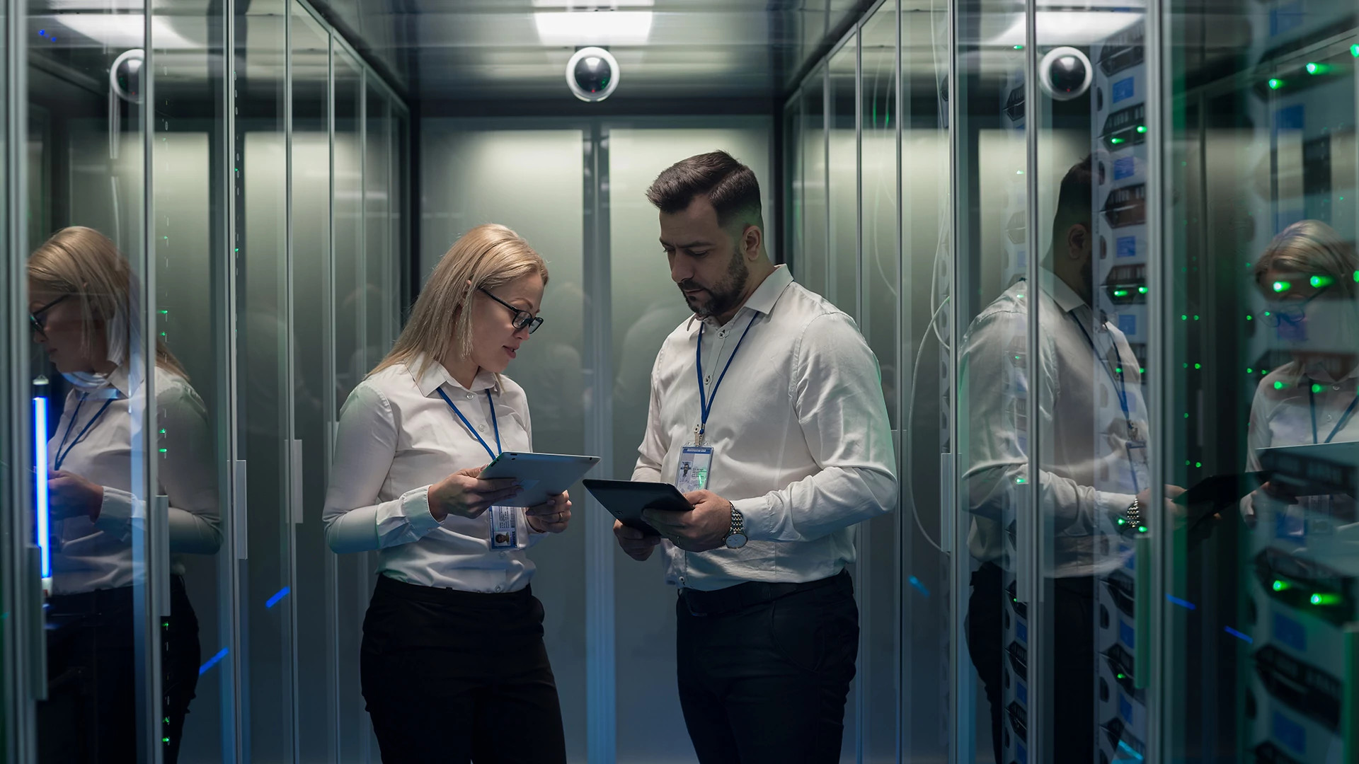 Two IT staff stand in a server room, using tablets to show unified security that is vendor agnostic.