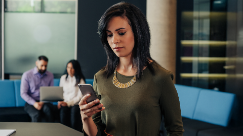 Una mujer sostiene un dispositivo móvil para el acceso remoto a los sistemas de seguridad de los arrendatarios en un edificio de apartamentos inteligentes.