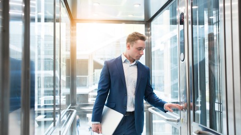 Un hombre de negocios con traje oscuro utilizando el control de acceso en ascensores con uno de los mejores sistemas de gestión de visitantes del mercado. 