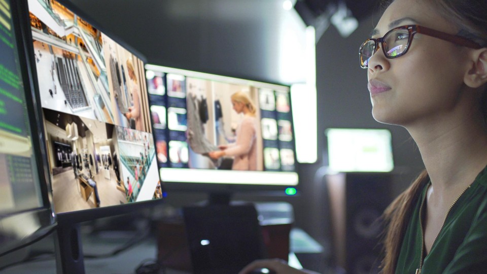 A person monitoring unified video feeds for store safety and loss prevention on multiple screens.