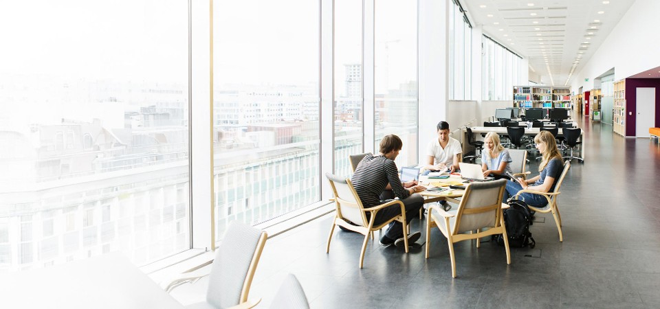 Studenten die samenwerken in een universiteitsbibliotheek, beschermd door een verbonden campusbeveiligingssysteem dat de veiligheid op de campus verbetert en het studentenleven ondersteunt.