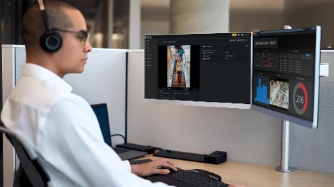 A person is monitoring store occupancy data on retail security solutions at a workstation.