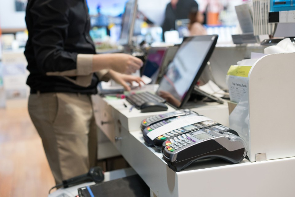 A store employee is conducting a POS investigation using security solutions for retail at the counter.