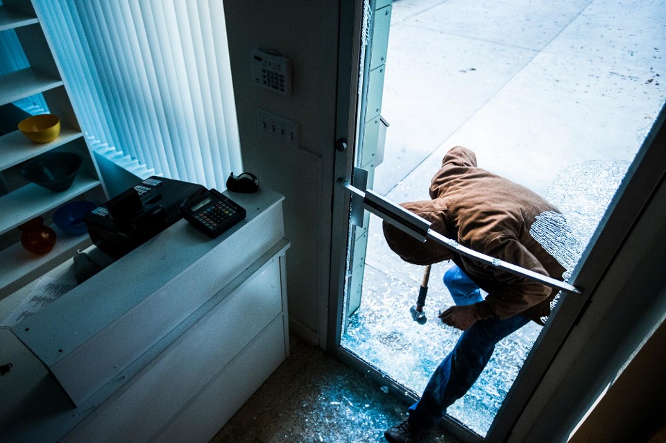 A person breaking a glass door triggers the store alarm system for immediate response.
