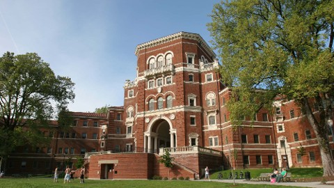 Red brick university building with smart campus solutions surrounded by greenery.